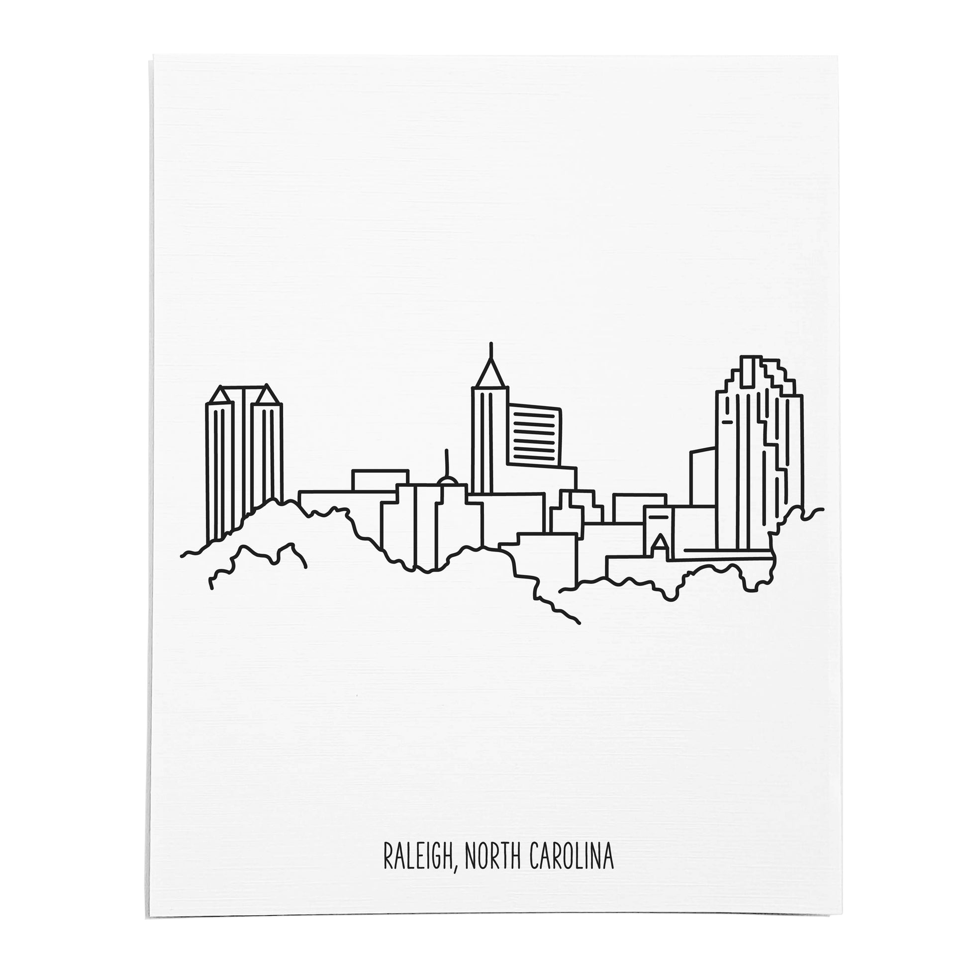 An art print featuring a line drawing of the Raleigh Skyline on white linen paper