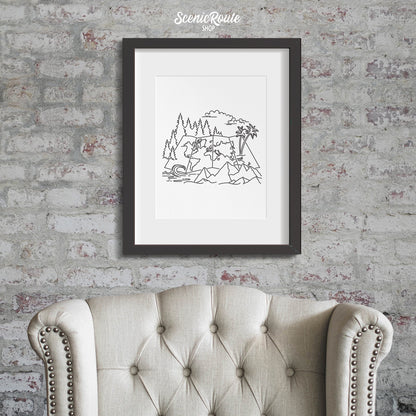 A framed line art drawing of the Adventure Map Drawing on a brick wall above a chair