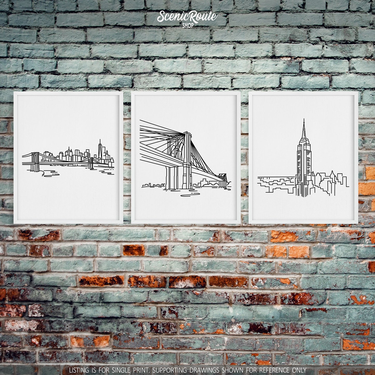 A group of three framed drawings on a brick wall. The line art drawings include the New York Skyline, Brooklyn Bridge, and Empire State Building