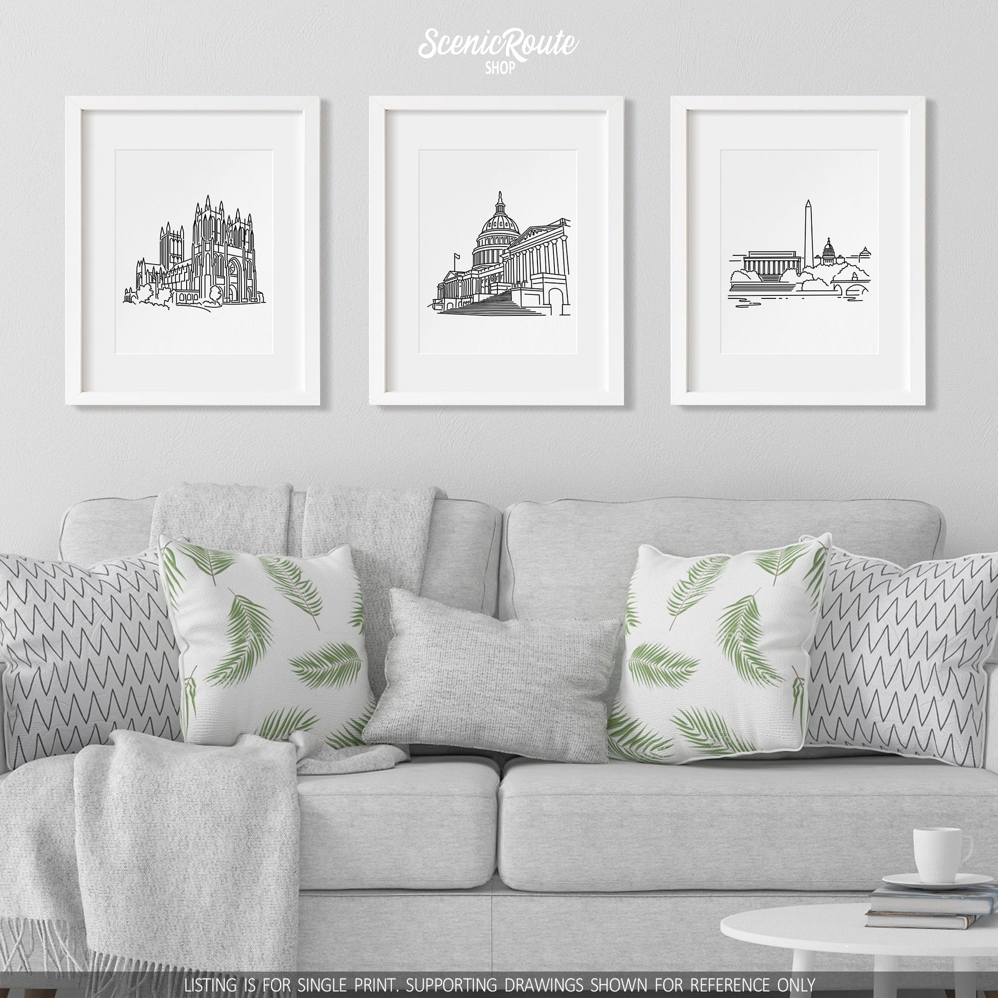 A group of three framed drawings on a white wall hanging above a couch with pillows and a blanket. The line art drawings include the National Cathedral, Capitol, and Washington Skyline