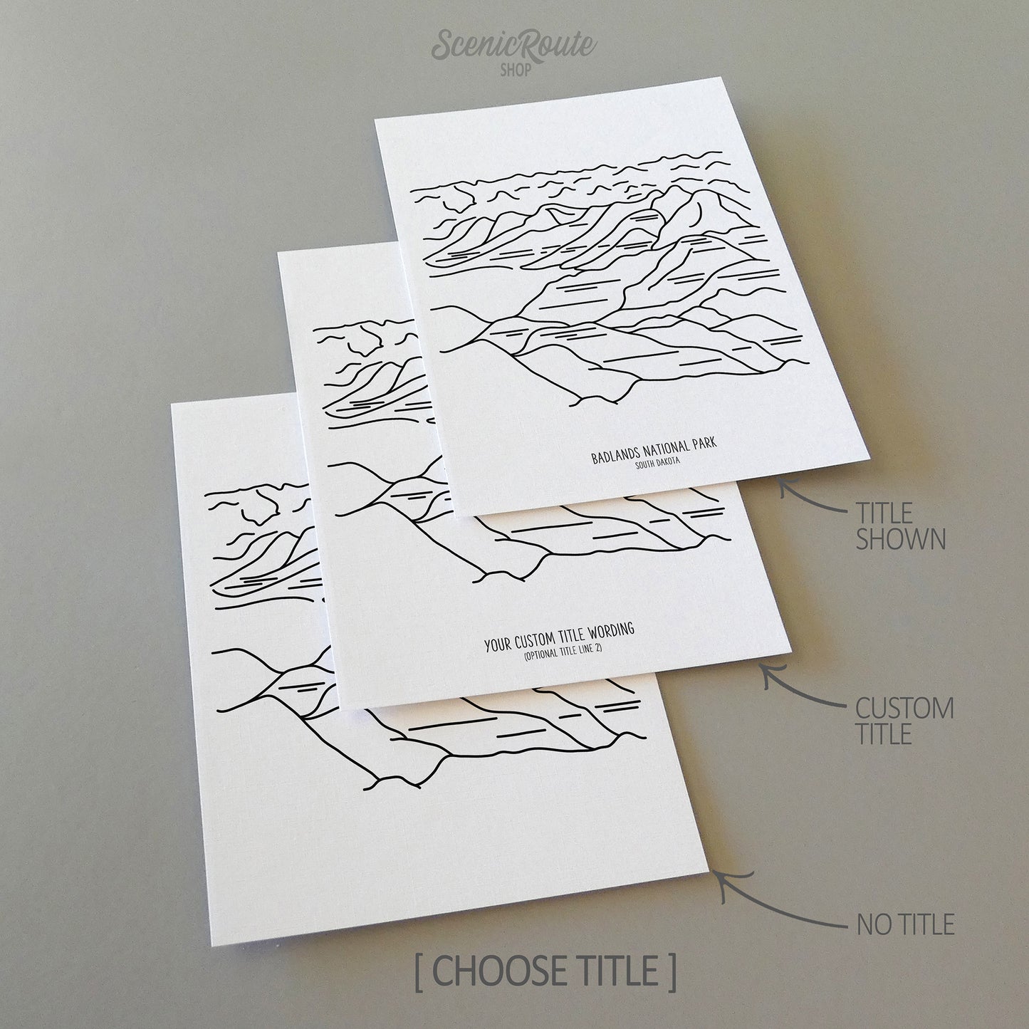 Three line art drawings of Badlands National Park on white linen paper with a gray background. The pieces are shown with title options that can be chosen and personalized.