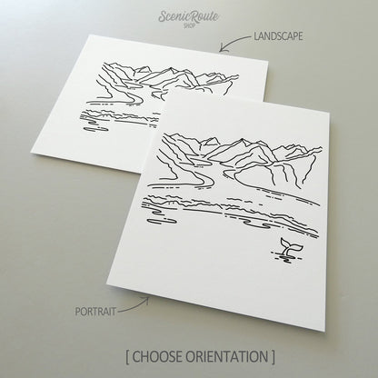 Two line art drawings of Glacier Bay National Park on white linen paper with a gray background.  The pieces are shown in portrait and landscape orientation for the available art print options.