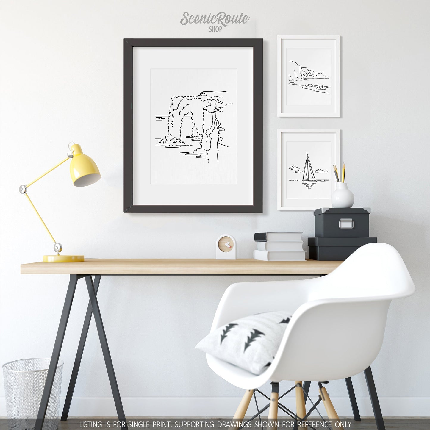 A group of three framed drawings on a wall above a desk. The line art drawings include Hawaii Volcanoes National Park, NaPali Coast, and Sailing