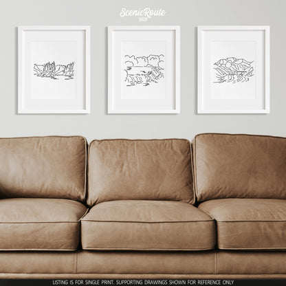 A group of three framed drawings on a wall above a couch. The line art drawings include Kenai Fjords National Park, Katmai National Park, and Wrangell Saint Elias National Park