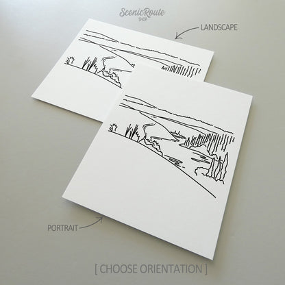 Two line art drawings of Kobuk Valley National Park on white linen paper with a gray background.  The pieces are shown in portrait and landscape orientation for the available art print options.