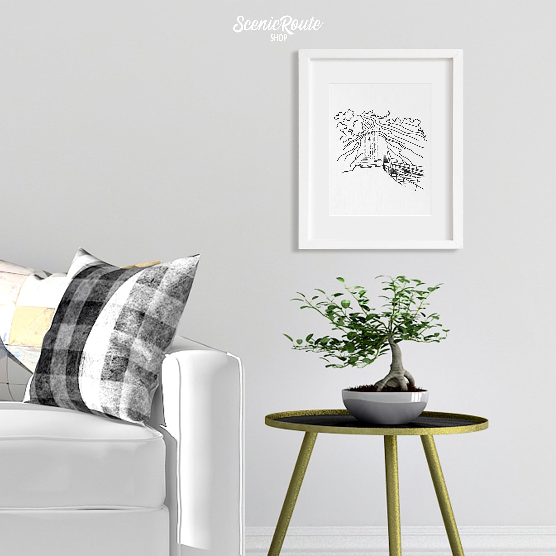 A framed line art drawing of Mammoth Cave National Park hanging over a side table with a plant