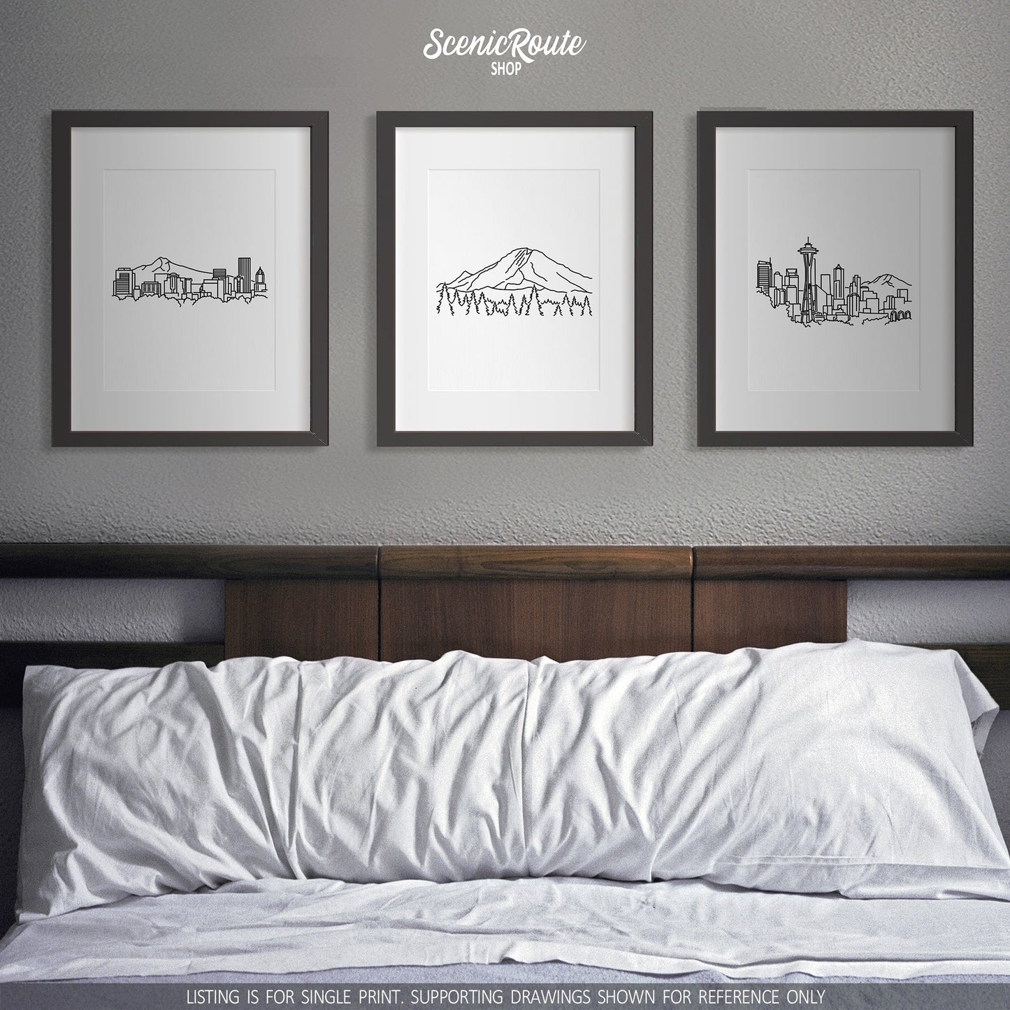 A group of three framed drawings on a white wall above a bed. The line art drawings include the Portland Skyline, Mount Rainier National Park, and Seattle Skyline